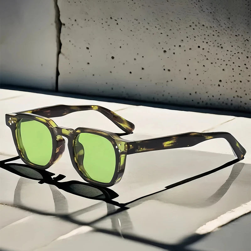 Lunettes de soleil vertes et monture écaille posées sur une surface blanche brillante